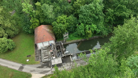 Small-hydroelectric-power-house-in-forrest-with-idyllic-stream-drone-pan