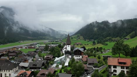 Beautiful-Swiss-Landscape---arial-shot-away-from-the-Saanen-Church-near-Gstaad,-Switzerland
