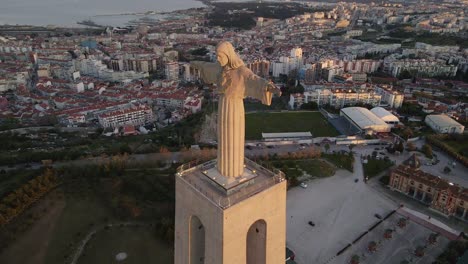 The-christ-statue-monument-of-Lisbon-in-sunset-light,-taken-by-drone