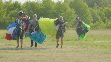 Slow-Motion-Adventurous-Spirits:-Smiling-Skydivers-and-Paragliders-Approach-the-Camera-After-a-Successful-Jump-in-Hel,-Jastarnia,-Poland