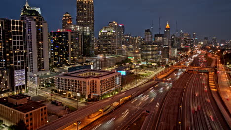 Atlanta-Georgia-Aerial-v883-dusk-to-night-hyperlapse,-busy-interstate-freeway-with-illuminated-downtown-and-midtown-cityscape-and-fast-traffic-light-trails---Shot-with-Mavic-3-Pro-Cine---May-2023