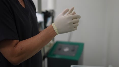 nurse-putting-gloves-on-her-hands,-in-operating-room