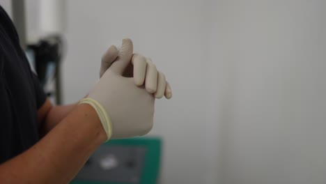 nurse-putting-gloves-on-her-hands,-in-hospital-operating-room