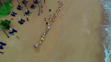 Topdown-scene-of-two-groups-playing-tug-of-war-on-the-beach-as-the-drone-camera-pans