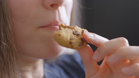 Close-up-view,-young-caucasian-woman-eating-chocolate-chip-cookie