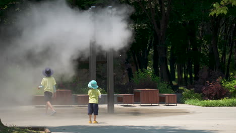 Kinder-Spielen-In-Der-Nähe-Eines-Außennebel-Kühlwassersprühsystems-Mit-Düsensprinklern-Im-öffentlichen-Yangjae-Foret-Park-In-Seoul,-Südkorea