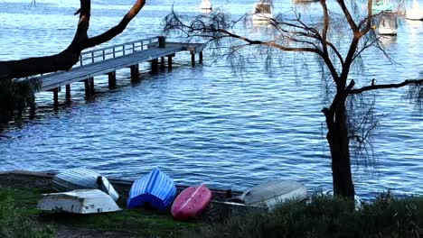 Upturned-Boats-on-beach-in-front-of-Long-Jetty-on-Swan-River-at-Peppermint-Grove,-Perth,-Western-Australia