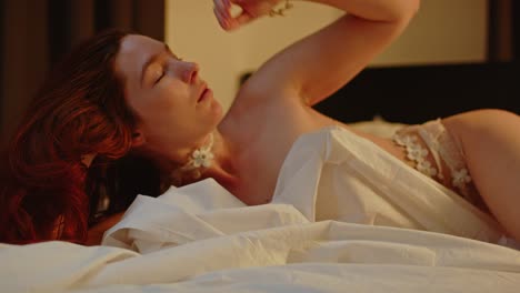 A-beautiful-redheaded-woman-is-nearly-nude-in-bed-and-seductively-plays-with-her-hair