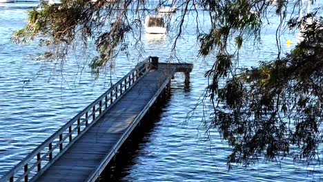 Looking-through-branches-of-boat-and-end-of-Long-Jetty-on-Swan-River-at-Peppermint-Grove,-Perth,-Western-Australia