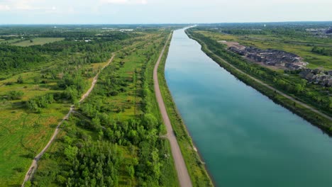 Welland-Canal-waterway-between-lush-green-trees-and-neighbourhood-into-distance