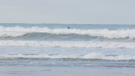 Surfers-are-waiting-for-perfect-waves-to-come-in-Caste-Point-Beach,-New-Zealand