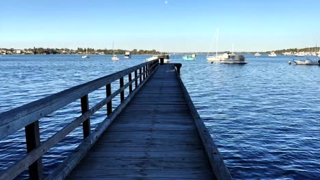 Looking-down-Long-Jetty-to-boats-on-Swan-River-at-Peppermint-Grove,-Perth,-Western-Australia