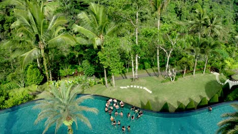 Active-girls-in-swimming-pool-water-aerial-drone-view-from-above,-Young-boys-and-girls-having-fun-on-tropical-family-vacation,-holiday-resort-concept