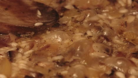 Close-Up-of-Mushroom-Risotto-Cooking-with-Wooden-Spoon-Lying-on-Top