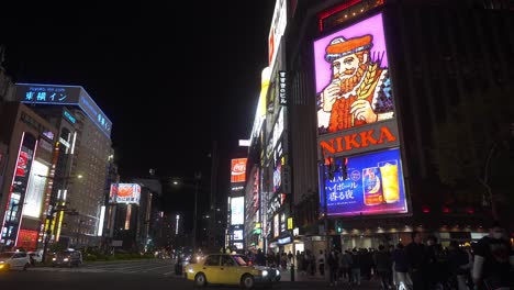 Nachtaufnahme-In-Susukino-Mit-Menschen,-Die-Neben-Dem-Neonbeleuchteten-Nikka-Whisky-Schild-Die-Straße-überqueren