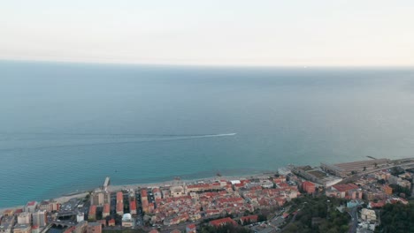 Aerial-of-beautiful-Italian-coastal-city-with-a-small-boat-sailing-through-a-blue-sea