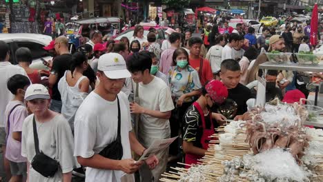 Gente-Apiñada-Alrededor-De-Vendedores-Ambulantes-Que-Venden-Calamares-En-Chinatown,-Bangkok
