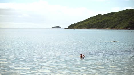 Amateurtaucher-Schwimmen-Am-Tartaruga-Strand-In-Búzios,-Brasilien,-Mit-Einem-Hintergrund-Aus-üppigen-Bergen-Und-Wolken