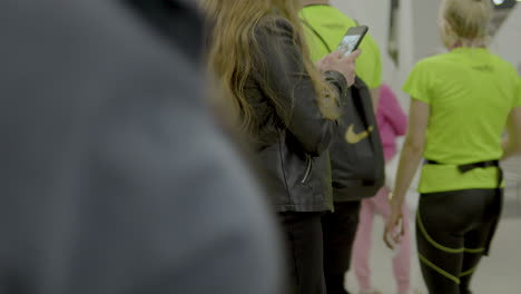 A-girl-holding-a-phone-in-both-hands-writes-a-message-while-waiting-for-a-passenger-at-an-airport-in-Gdansk