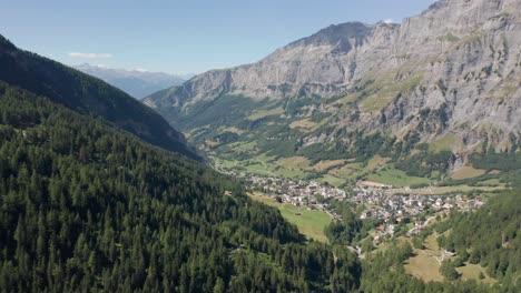 Aerial-of-beautiful-small-Swiss-town-in-a-green-valley-surrounded-by-mountains