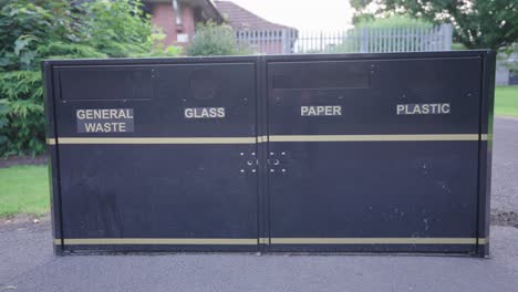 Vier-Schwarze-Entsorgungsbehälter-Aus-Metall-Für-Abfall,-Glas,-Papier-Und-Kunststoff