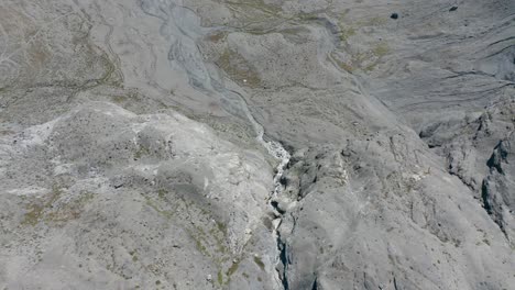 Luftaufnahme-Von-Oben-Nach-Unten-Eines-Kleinen-Wasserfalls,-Der-Durch-Ein-Trockenes-Berggebiet-Fließt