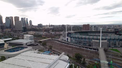Aerial-panning-shot-from-left-to-right,-starting-on-Melbourne's-city-skyline-and-ending-on-Melbourne-Rectangular-Stadium