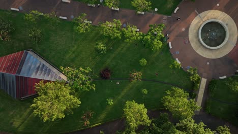 Overhead-drone-shot-of-friends-playing-frisbee-in-park-at-sunset
