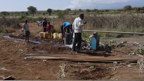 Afrikaner-Sammeln-Trinkwasser-In-Plastikkrügen-Am-Bohrlochbrunnen,-Loitokitok,-Kenia