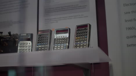 Computer-museum,-on-a-white-table-there-are-displayed-calculators,-behind-are-descriptions-and-their-history