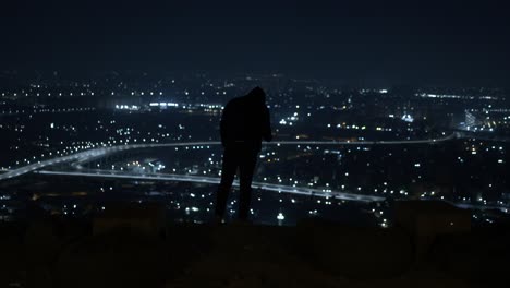 Man-in-Black-Jacket-Standing-on-a-top-view-overlooking-the-expressway-at-midnight