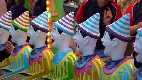 Popular-carnival-games,-laughing-clowns-with-its-mouth-wide-open,-turning-its-head-from-left-to-right-and-right-to-left,-booth-owner-passing-on-the-prize-to-the-customer