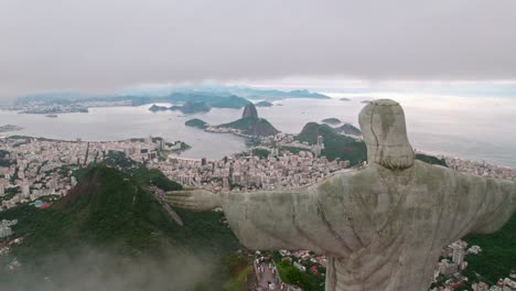 Aerial-view-dolly-in-passing-by-the-side-of-Christ-the-Redeemer-towards-Rio-de-Janeiro,-Brazil-on-a-cloudy-day