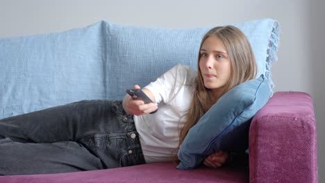 Attraktive-Frau-Chillt-Auf-Der-Couch-Mit-TV-Fernbedienung,-Vorderansicht