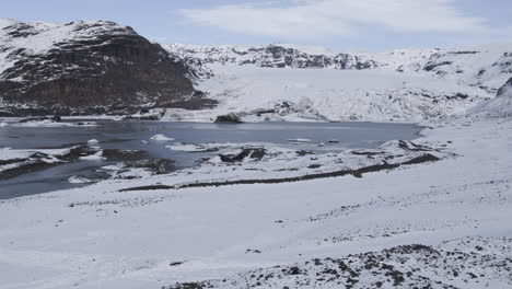 Langsamer-Dolly-über-Einem-Windmarker,-Der-Einen-Zugefrorenen-See-In-Der-Isländischen-Landschaft-Enthüllt