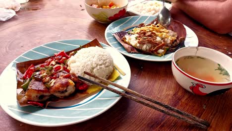 Eating-authentic-traditional-khmer-food-for-breakfast-of-Trei-boeng-kanh-chhet-or-spicy-fried-fish-and-Bai-sach-chrouk-or-pork-with-steamed-rice