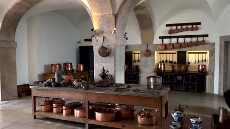 Old-historic-kitchen-at-Pena-Palace-in-Sintra-with-pan-and-pot-of-copper,-panning-shot