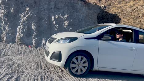 Peugeot-108-driving-up-a-steep-mountain-road-on-a-sunny-day-in-Santorini