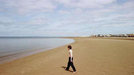 Young-man-stretches-as-he-walks-towards-the-calm-water-of-the-sea
