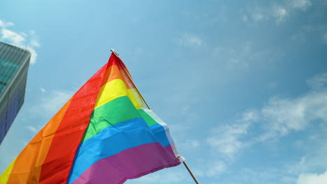 Close-up-upwards-view-of-colorful-rainbow-pride-flag-against-blue-sky