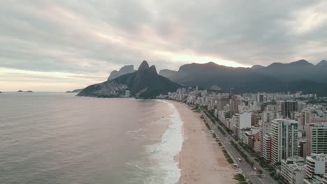 Aerial-view-establishing-the-beaches-of-Ipanema-and-Leblon-with-an-epic-cloudy-sunset-with-the-hill-two-brothers-in-the-background,-Rio-de-Janeiro-Brazil