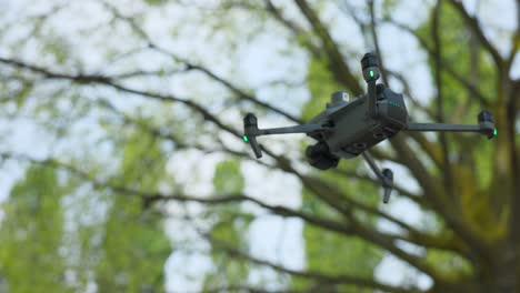 Low-angle-close-up-view-of-DJI-Mavic-3E-enterprise-drone-for-photogrammetry-flying-with-trees-in-background