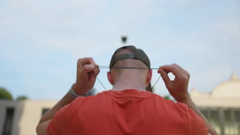 View-Behind-Adult-Male-Who-is-Tightening-Lanyard-Around-Back-Of-Neck