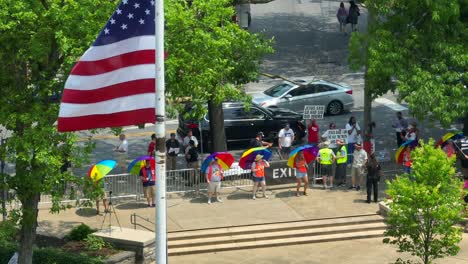 Luftaufnahme-Der-Amerikanischen-Flagge-Beim-LGBTQ-Pride-Parade-Festival-Mit-Menschen-Und-Regenbogenfarbenen-Regenschirmen