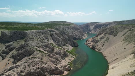 Green-river-Zrmanja-meandering-among-karst-canyon-slopes,-an-aerial-footage,-Croatia,-Zadar-county