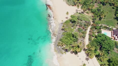 Aerial-birds-eye-shot-over-PLAYA-COLORADA-with-sandy-beach-and-clear-blue-water-of-sea-in-summer---tilt-up-shot---Tropical-landscape-with-hotel-resort-and-swimming-pool