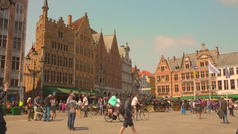 People-Touring-Around-The-Ancient-Market-Square-On-A-Sunny-At-The-Old-Town-Of-Bruges-In-Belgium