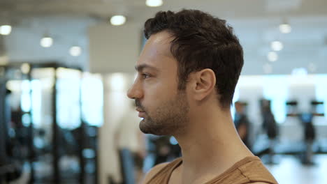 Face-Close-up-of-Thoughtful-Sporty-Bearded-Man-Standing-in-Modern-Gym---parallax-slow-motion