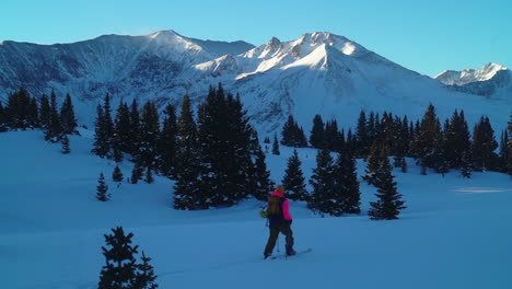 Cinematic-stunning-Colorado-early-morning-shaded-Rocky-Mountain-backcountry-skier-split-boarder-up-hill-hiking-fresh-snow-top-peaks-light-Copper-Breckenridge-Aspen-Vail-follow-zoom-in-out-pan