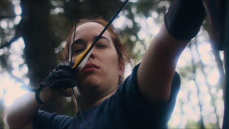 Archery-woman-pulls-and-shoots-her-bow-low-angle-close-shot